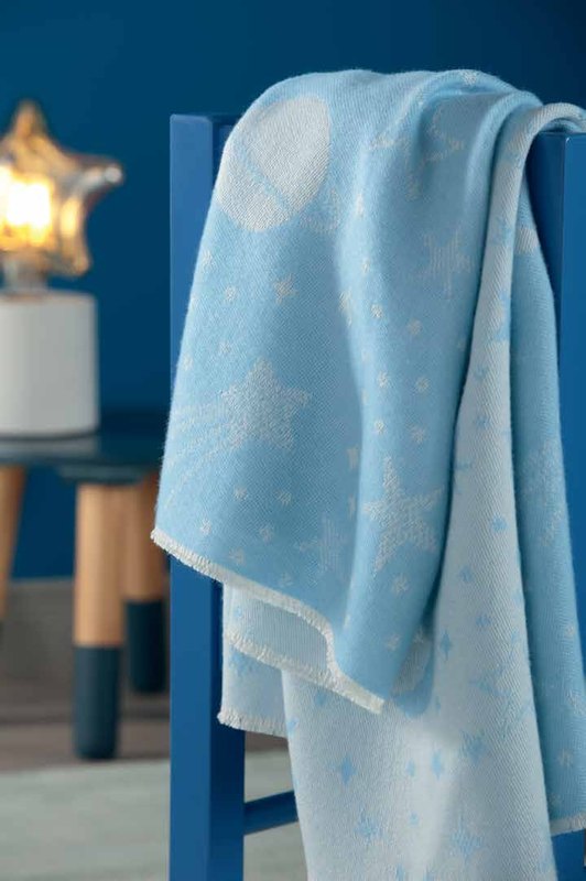 Голубой детский плед Biederlack LOVELY SWEET UNIVERSE BLUE со звёздами перекинут через синий стул, рядом ночник в виде звезды
