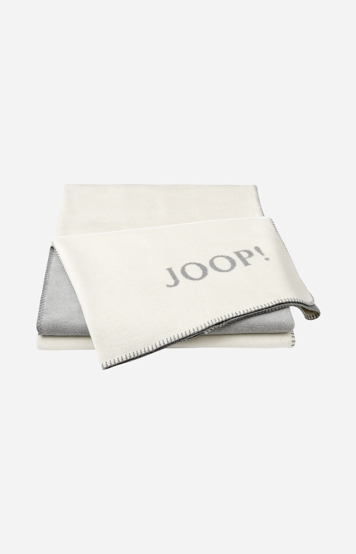Плед JOOP! MELANGE-DOUBLEFACE в расцветке Natur-Silber, двусторонний, с бахромой и вытканным логотипом JOOP!, сложен веером