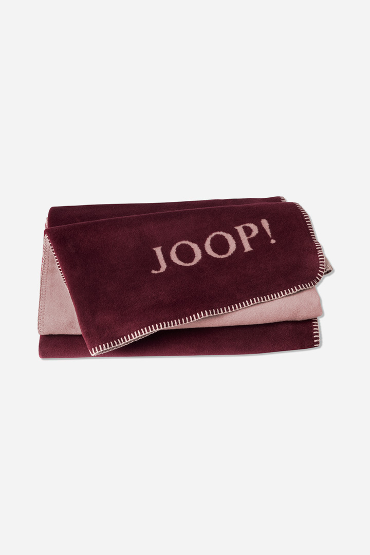 Плед JOOP! UNI-DOUBLEFACE в расцветке Rouge/Nude, двусторонний, с бахромой и вытканным логотипом JOOP!, сложен веером