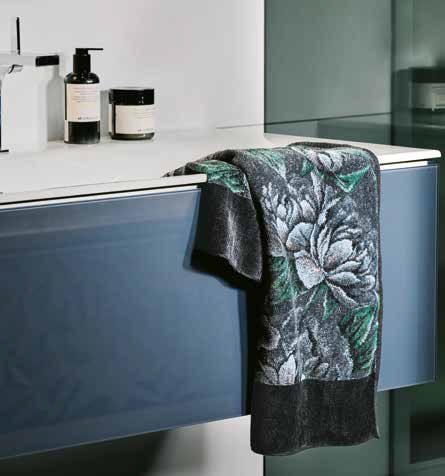 Полотенце Feiler DARK PEONY, тёмно-графитовое с рисунком пионов, висит на современной ванной тумбе рядом с флаконами